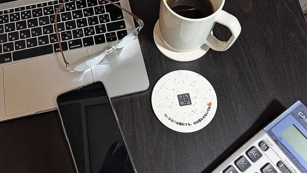 デスクにロゴ入り珪藻土コースター とコーヒー&マグカップ、PC、スマホ、計算機